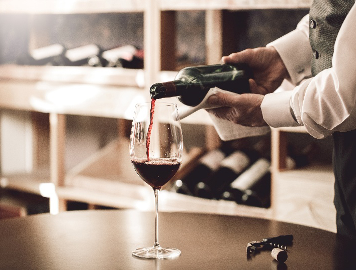 Osoba nalewająca wino do kieliszka